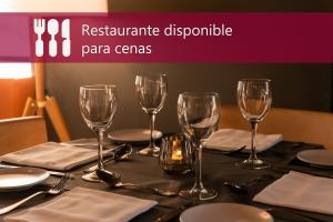 a table with wine glasses and plates and a candle at Aparthotel Atenea Valles in Granollers