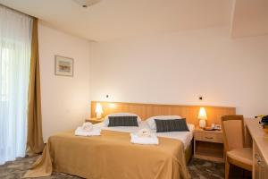 a hotel room with two beds with towels on them at Hotel Flores in Poreč