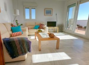 ein Wohnzimmer mit einem Sofa und einem Couchtisch in der Unterkunft Terraza Trafalgar Apartamento tipo penthouse con enorme terraza y vistas al mar in Conil de la Frontera