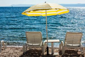 Dos sillas y una sombrilla en la playa en Villa Bol Waterfront - Contemporary 6 Bedroom Villa - Private Pool - Ocean Front - AC en Bol