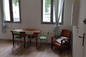 a table and chairs in a room with a table and two windows at Appartement cosy proche du CHU in Rouen +2 photos