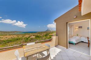 um pátio com uma mesa de madeira e cadeiras numa varanda em Residence Hotel Lu Nibareddu em San Teodoro