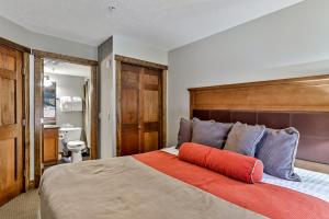 a bedroom with a large bed with an orange pillow on it at Fenwick Vacation Rentals Spacious Mountain 2 Bedroom with Hot tub in Canmore