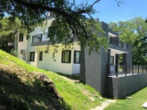 un gran edificio blanco en una colina con patio en COMPLEJO AYRES DE MAYU SUMAJ, en Villa Carlos Paz