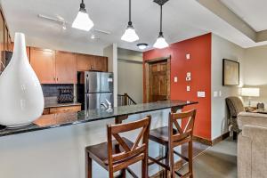 a kitchen with a bar with chairs and a counter top at Fenwick Vacation Rentals Spacious Mountain 2 Bedroom with Hot tub in Canmore