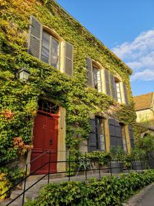 un edificio cubierto de hiedra con una puerta roja en Maison d'hôtes - Les Tillets en Bois-Sainte-Marie