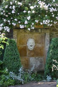 un mur en pierre avec un visage orné de fleurs dans l'établissement Maison d'hôtes - Les Tillets, à Bois-Sainte-Marie