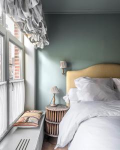 a bedroom with a bed with a yellow headboard and a window at Guesthouse Dijver - Serene Escape in the Heart of Historic Bruges in Bruges