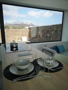 una mesa con platos y copas de vino. en Villa Volcán, en Lajares