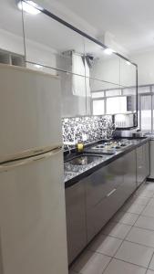 een grote keuken met roestvrijstalen werkbladen en apparatuur bij Apto no Ed. Alexandra I in Guarujá
