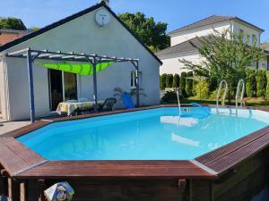 a swimming pool with a wooden deck and a house at 1 chambre avec salle de bain privative ds maison plain-pied 105m2 à Montfaucon 10 minutes de Besancon in Montfaucon