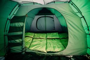 a green and white tent with a bed in it at The ESN Kingsday Campsite in Amsterdam
