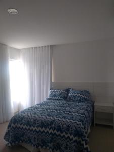 - une chambre avec un lit doté d'une couette bleue et d'une fenêtre dans l'établissement Quintas de Sauipe, Casa F7, à Costa do Sauipe