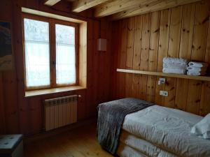 Schlafzimmer mit einem Bett, einem Fenster und Holzwänden in der Unterkunft Apartamentos Mauberme in Salardú