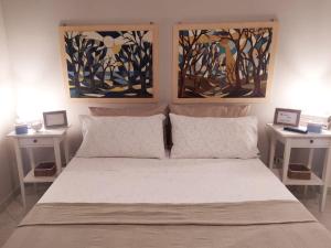 a bedroom with a bed with two paintings on the wall at A due passi dal mare in Moneglia