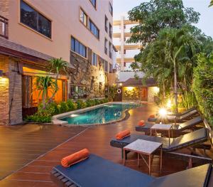 una piscina all'aperto con tavoli e sedie accanto a un edificio di Orchid Garden Hotel a Patong Beach