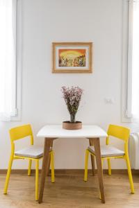 a table with two chairs and a vase of flowers on it at Canonica Suites in Bologna