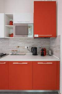 a kitchen with red cabinets and a microwave at Canonica Suites in Bologna