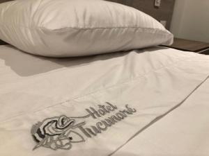 a bed with a pillow with the words hilton involuntary at Hotel Tucunaré in Inírida