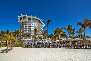 ein Hotel am Strand mit Tischen und Sonnenschirmen in der Unterkunft Bellwether Beach Resort in St Pete Beach