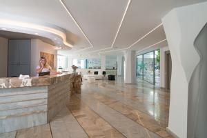 a woman standing at a counter in a lobby at Alia Beach Hotel by Estia in Hersonissos