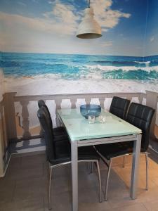 une table avec des chaises et une peinture de l'océan dans l'établissement Vier Jahreszeiten Haus 1 Whg 20, à Großenbrode