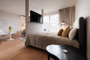 Schlafzimmer mit einem Bett, einem TV und einem Tisch in der Unterkunft SAXX Apartments Leipzig in Leipzig