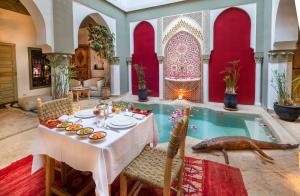 une salle à manger avec une table et une piscine dans l'établissement Riad Loudaya & Spa, à Marrakech