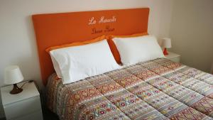 ein Bett mit orangefarbenem Kopfteil und zwei weißen Kissen in der Unterkunft La Marocella in Capri