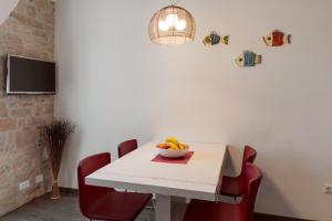 a table with red chairs and a bowl of fruit on it at Apartman Arca in Rovinj