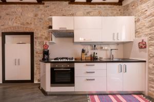 a kitchen with white cabinets and a stove at Apartman Arca in Rovinj