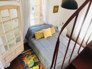 Habitación pequeña con cama con almohadas amarillas en Casa Palacio, Arte e Historia en Buenos Aires