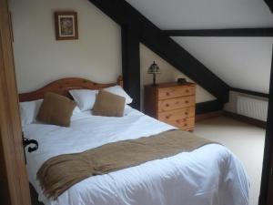 a bedroom with a white bed and a dresser at Swallows Nest Stanbury Wharf in Holsworthy