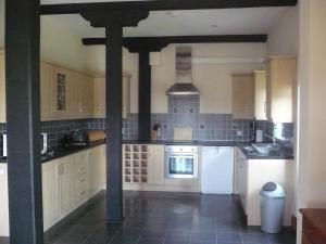 a large kitchen with white appliances and wooden beams at Swallows Nest Stanbury Wharf in Holsworthy