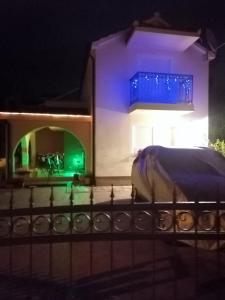 une maison avec une clôture devant elle la nuit dans l'établissement Apartment Ninić, à Srima