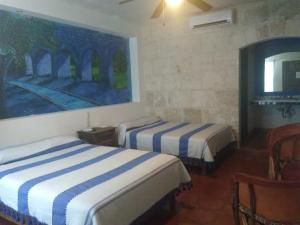 a bedroom with two beds and a painting on the wall at Casa Maru Hotel in Parras de la Fuente