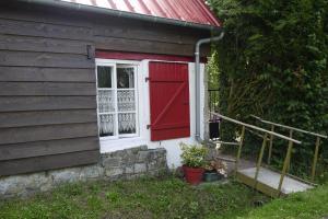 Petite maison Normande في Bellou-en-Houlme: باب احمر ونافذة بجانب المنزل