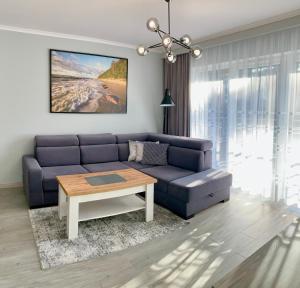 salon z niebieską kanapą i stołem w obiekcie Apartament RELAX w Pogorzelicy
