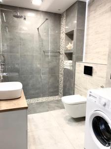 a bathroom with a shower and a washing machine at Apartament RELAX in Pogorzelica