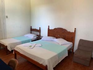 a room with two beds and a chair at Hotel Valenciano in Valença