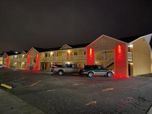 dois carros estacionados em frente a um edifício com luzes vermelhas em 1st Interstate Inn em Grand Junction