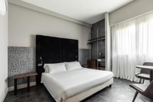 Un dormitorio con una gran cama blanca y una mesa en Anusca Palace Hotel en Castel San Pietro Terme