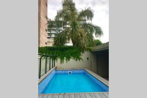 - une piscine à côté d'un bâtiment avec un palmier dans l'établissement Hermoso NUEVO con PISCINA, Balcón y Patio, à Rosario