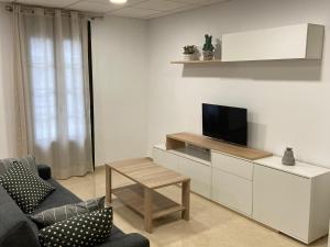 a living room with a tv and a couch and a table at Os Arcos - Apartamentos Turísticos in Portomarin