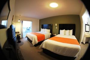 a hotel room with two beds and a television at Hotel Nuvo in Saltillo