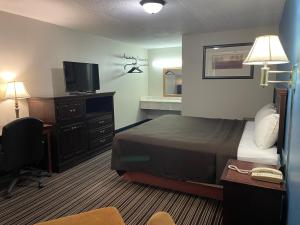 a hotel room with a bed and a television at Budget Inn Motel in Bourbon