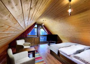 a bedroom with a wooden ceiling with a bed and a television at High Tatras Chalet in Štrbské Pleso