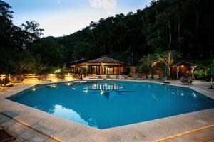 a large blue swimming pool in front of a house at Hotel Caminhos de Itaipava in Itaipava