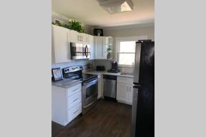 a kitchen with white cabinets and a black refrigerator at Belmont NC Riverfront 2-Bedroom Garden Suite in Charlotte