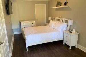 a bedroom with a white bed and a night stand at Belmont NC Riverfront 2-Bedroom Garden Suite in Charlotte
